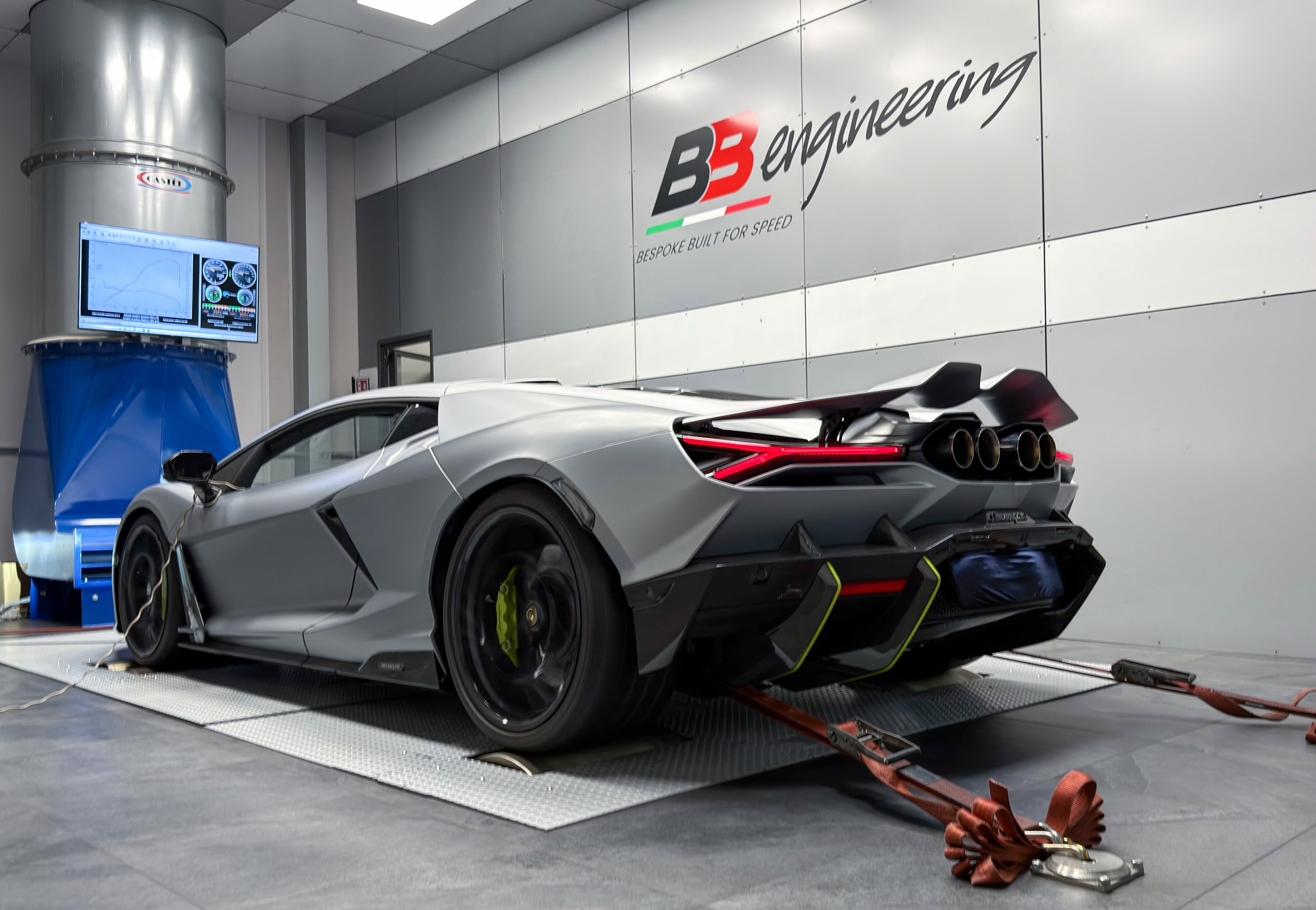 Grey Lamborghini strapped to a chassis dynamometer with a live power curve on the cell monitor